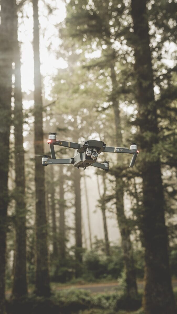 gray and black DJI Mavic Pro quadcopter drone on mid top air near forest at daytime
