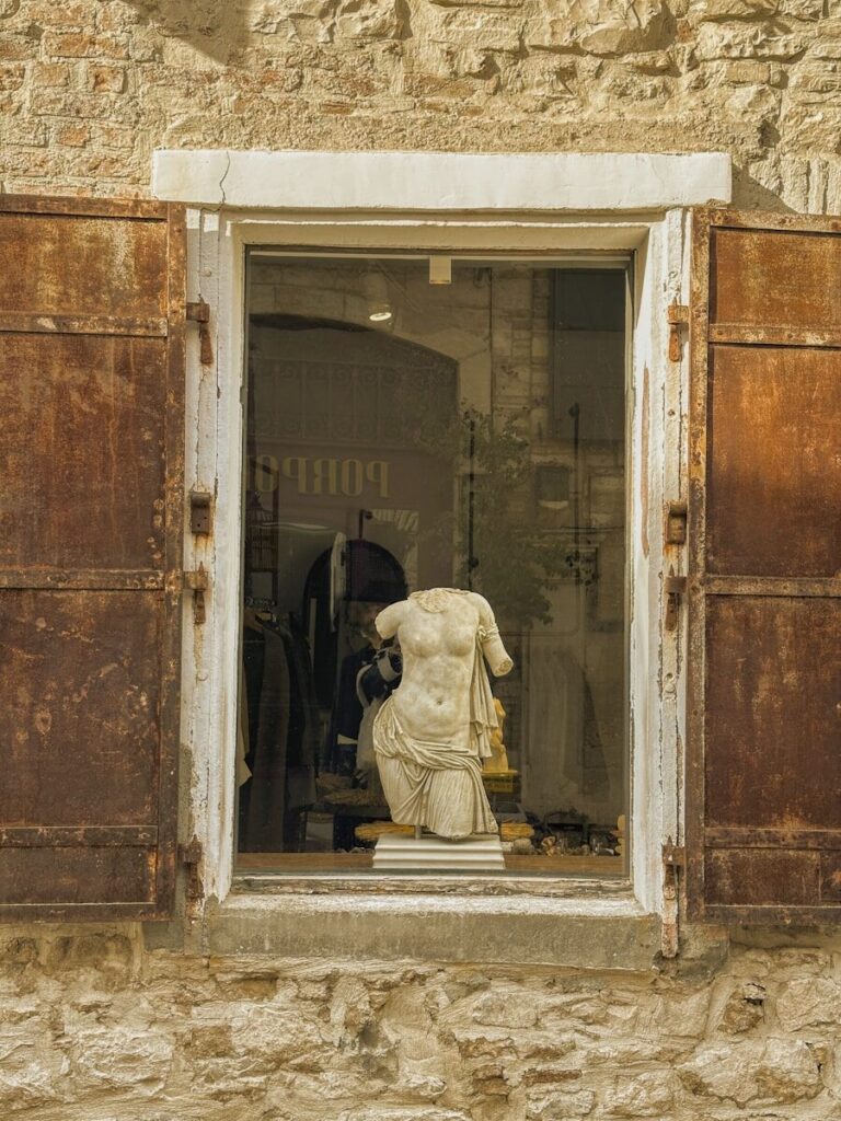 A statue of a woman in a window with shutters