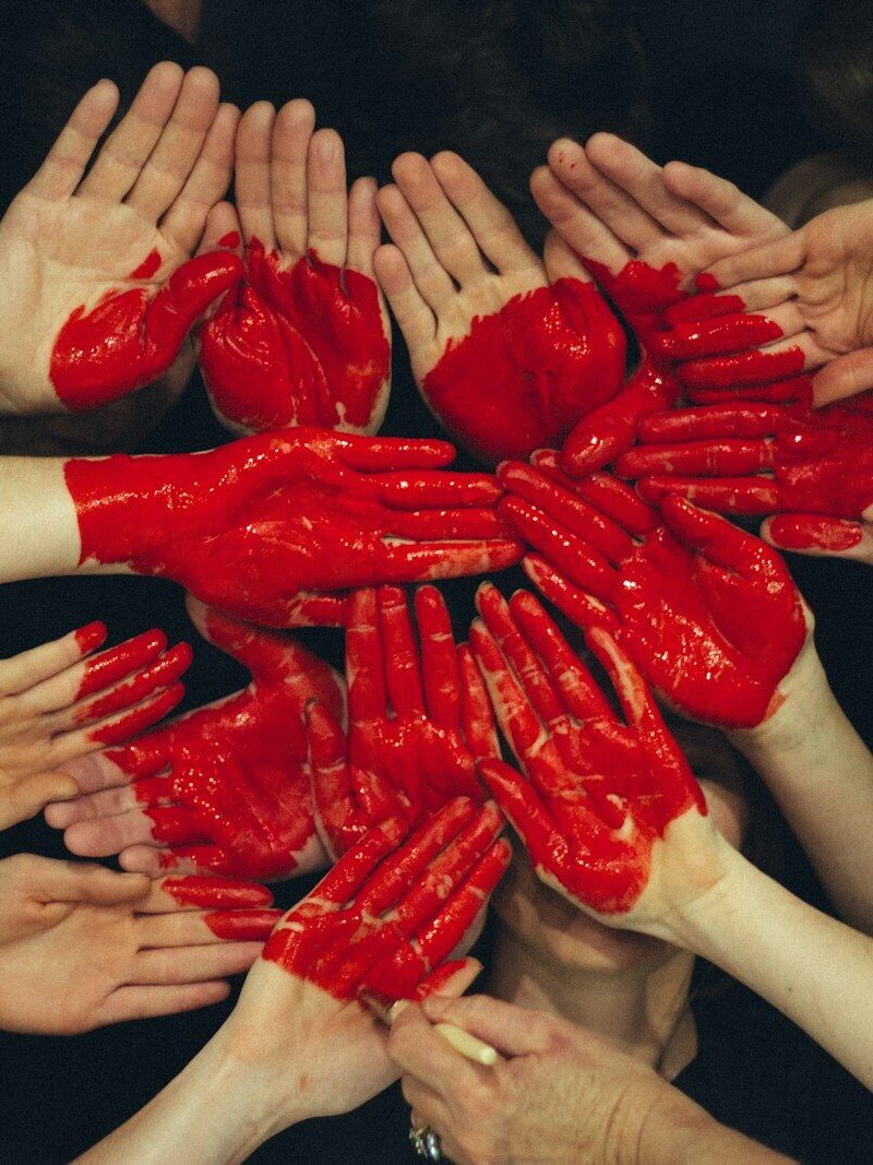 hands formed together with red heart paint