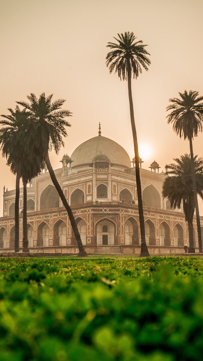 white and brown dome building near green and coconut tree grass at daytime