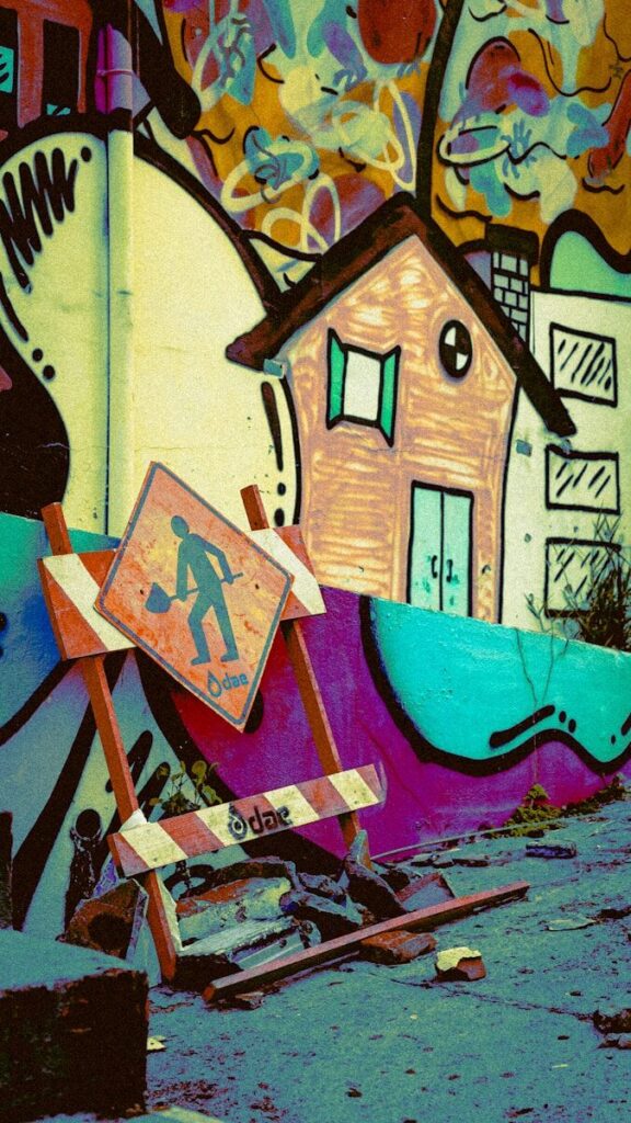 Colorful graffiti wall with a house drawing and construction sign.